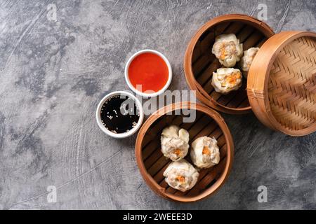 Chinese steamed dumplings or  Dim Sum in bamboo steamer on dark abstract background Stock Photo