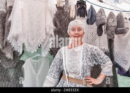 Portrait of senior white woman selling warm knitted items made of wool and fluff at traditional fair Stock Photo