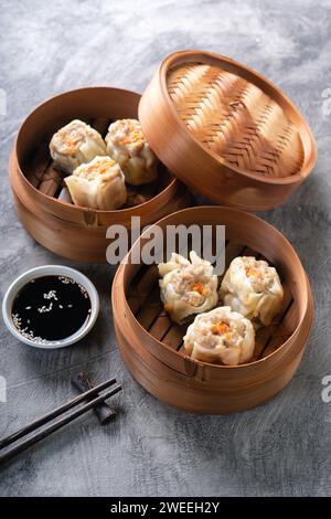 Chinese steamed dumplings or  Dim Sum in bamboo steamer on dark abstract background Stock Photo