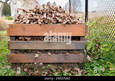 A composter made of wooden boards filled with dry leaves. Stock Photo