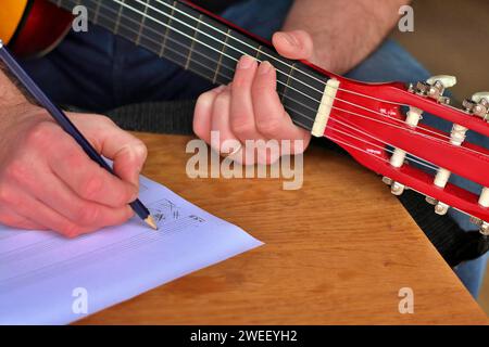 Songwriter Composing A Song For Guitar Writing Down Notes On Scoresheet Stock Photo