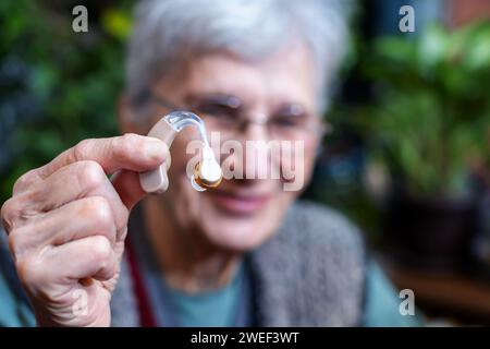 smiling senior woman showing a hearing aid Stock Photo