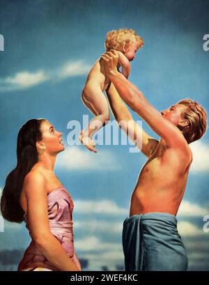 Jean Simmons, Donald Houston, and baby Peter Wood star in 'The Blue Lagoon' (1949), a romantic adventure film. In this movie, Simmons and Houston play two young cousins, Emmeline and Michael, who are shipwrecked on a tropical island along with baby Paddy, portrayed by Peter Wood. As they grow up in this isolated paradise, their childlike friendship evolves into deeper love. Stock Photo