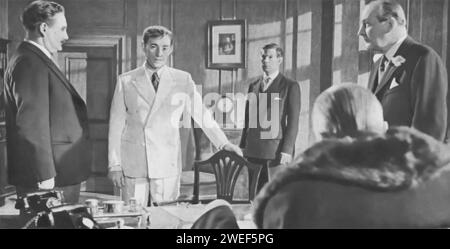 Howard Marion-Crawford, Alec Guinness, Michael Gough, Ernest Thesiger, and Cecil Parker star in 'The Man in the White Suit' (1951), a British satirical comedy. Alec Guinness plays Sidney Stratton, an eccentric chemist who invents an indestructible and dirt-repelling fabric, which disrupts the textile industry. Parker portrays Alan Birnley, a mill owner, Gough is Michael Corland, a rival manufacturer, Thesiger plays Sir John Kierlaw, and Marion-Crawford appears as Cranford, a supportive lab technician. Stock Photo