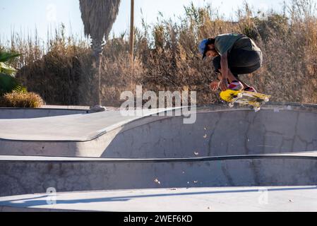 Fall skate vibes: Yellow skateboarder catches air, leaves swirl in the dynamic urban skate park Stock Photo