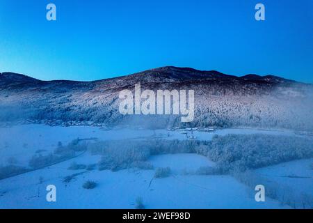 Early morning aerial view towards Kocevski rog ridge and primeval forest after heavy snowfall, morning fog still above the valley, Slovenia Stock Photo