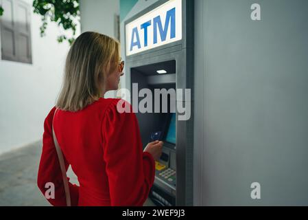 Woman using ATM on the street. Stock Photo
