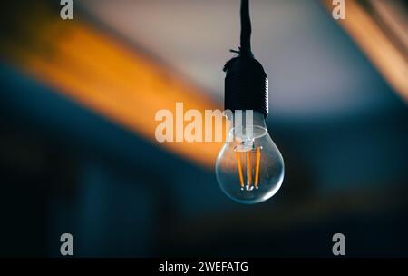 Incandescent light bulb with a medium-sized E27 hanging on wire. Stock Photo