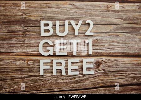 Buy 2 Get 1 Free alphabet letters on wooden background Stock Photo