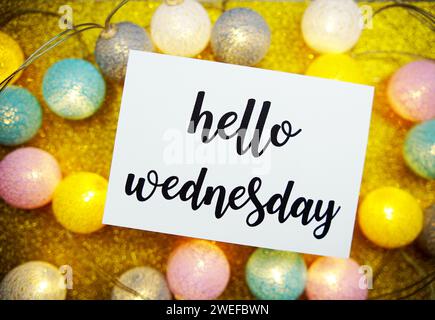 Hello Wednesday text on paper card top view on yellow bokeh background Stock Photo