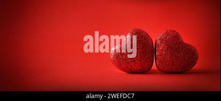 Background two red glitter hearts on red gradient background. Front view. Stock Photo