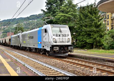 Two Captrain Italia Bombardier TRAXX DC3 class E.494 electric locomotives pass Stresa station with a northbound freight train. Stock Photo