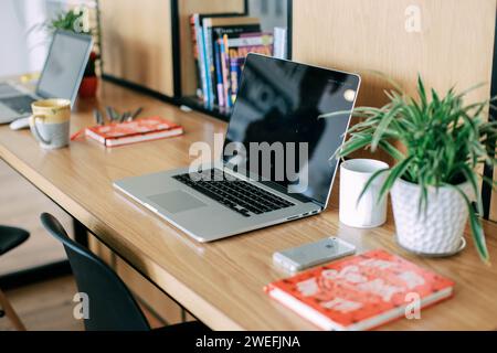 An image of two laptops side by side on a desk in front of a bookcase Stock Photo
