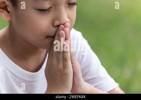 Little boy with Bible praying and close your eyes in praying. Prayer to pray. Children pray with folded hands. Stock Photo