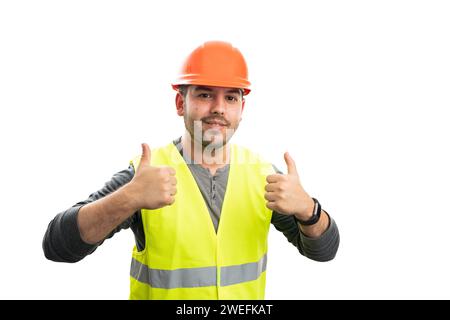 Friendly male constructor smiling waring uniform orange safety helmet and vest showing double thumb-up like gesture isolated on white background Stock Photo