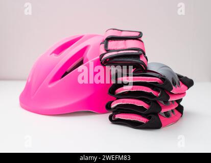 Pink helmet, knee and hand protection. Concept set of protection for roller skating, cycling and scooter. Stock Photo