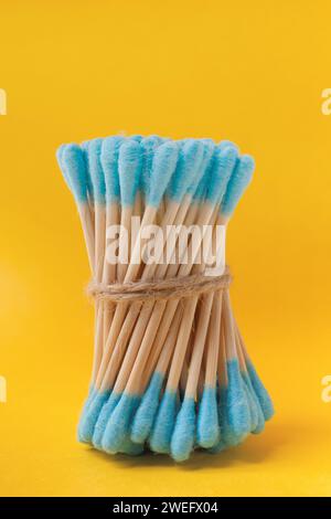 A bunch of blue bamboo cotton swabs buds sticks on a yellow background. The concept of hygiene items from natural, environmentally friendly Stock Photo