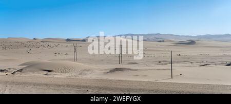 landscape with power lines and sand dunes in Sperrgebiet desert, shot in bright late spring light near Luderitz, Namibia, Africa Stock Photo