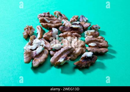 crashed walnuts isolated on green background Stock Photo