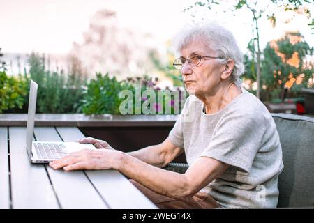 old woman using laptop on terrace Stock Photo