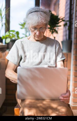 old woman using laptop on terrace Stock Photo