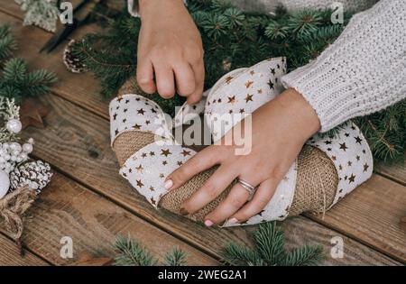 Female hands making beautiful christmas wreath on rustic wooden table Stock Photo