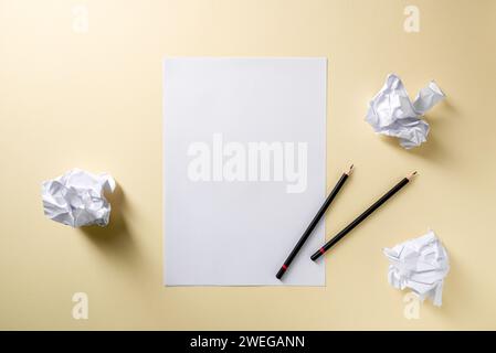 Blank writing sheet with pen and crumpled paper balls lay flat on yellow background Stock Photo