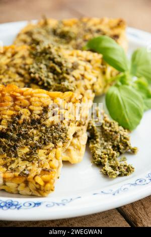 Slices of fried tempeh with a vegan arugula pesto. Stock Photo