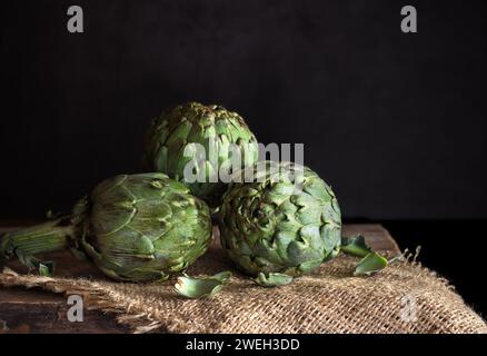 Fresh artichokes hearts on linen table - dark and moody tone Stock Photo