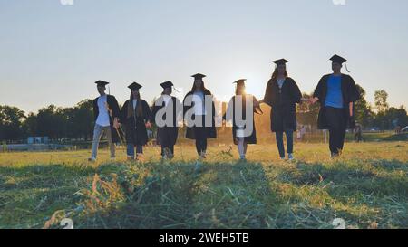 Graduate students walking through an evening meadow at sunset. Stock Photo