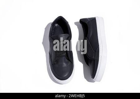 black sneakers on a white background top view with hard shadows. Women shoes. Stock Photo