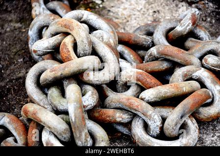 Thick, strong ship's chain lays on a dock in Astoria, Oregon.  Conceptual image illustrating strength, connection, linked, and unbreakable. Stock Photo