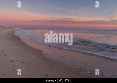 Waves gently lapping the shore at Indian River Inlet at sunrise, Delaware Seashore State Park between Bethany Beach and Dewey Beach, Delaware Stock Photo