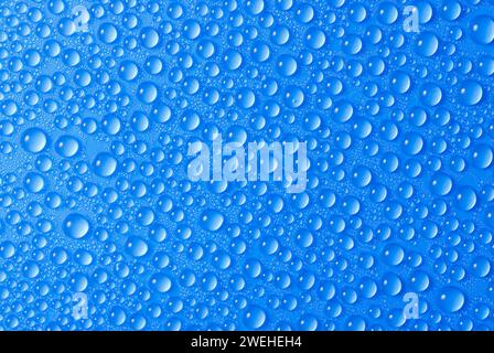 many small blue drops of water on a blue surface Stock Photo