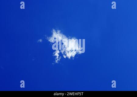 a single young small fluffy white fair weather cloud, Cumulus humilis, just forming in the blue sky Stock Photo
