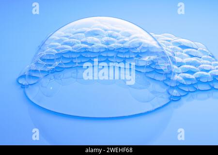 one large and many small soap bubbles on light blue water Stock Photo