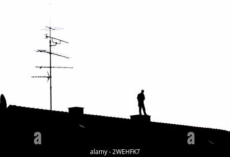 a man stands on the roof of an apartment building in Obergiesing and writes something down in a notebook, silhouette, Munich, Bavaria, Germany Stock Photo