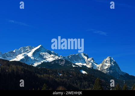Mountain panorama of the Wetterstein mountain range in spring, with Alpspitze on the left, Zugspitze in the center and Waxenstein on the right Stock Photo