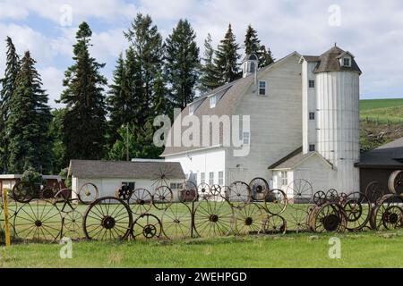 Uniontown, WA, USA - May 24, 2023; Wheel fence by Steve Dahmen and farm building at Artisans at the Dahmen Barn Stock Photo