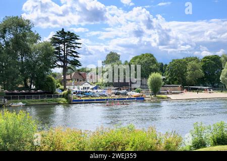 Four young women in a rowing boat on the River Thames in summer outside The River Club between Hampton Court and Kingston, England, UK Stock Photo