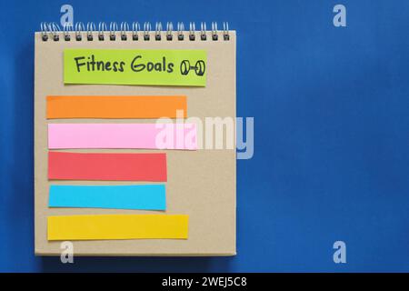Fitness goals concept. Checklist of goals in note pad in blue background with copy space. Stock Photo