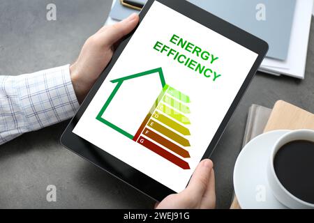 Energy efficiency. Man using tablet with colorful rating on display at table, closeup Stock Photo