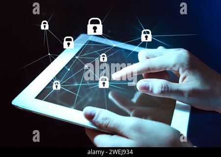 Privacy protection. Woman using tablet on dark background, closeup. Digital scheme with padlocks over device Stock Photo