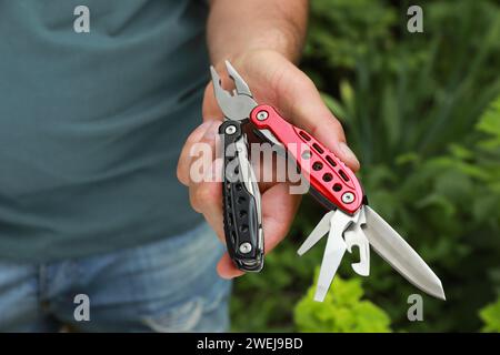 Man holding compact portable multitool outdoors, closeup Stock Photo