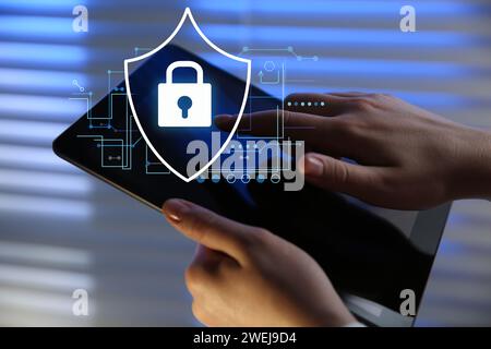 Privacy protection. Woman using tablet in office, closeup. Digital scheme with illustration of padlock in shield Stock Photo
