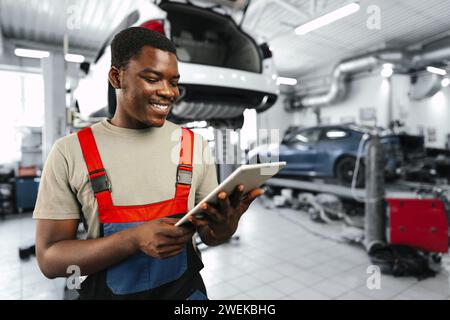 Young African auto mechanic using digital tablet in a car service Stock Photo