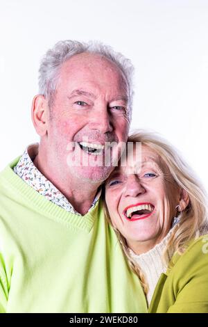 This delightful image captures the radiant joy of a senior couple sharing a close and happy embrace. Their faces are lit up with wide, genuine smiles, reflecting a deep and abiding happiness. The man and woman are dressed in bright, cheerful clothing that adds to the vibrant, positive energy of the moment. Their laughter and physical closeness speak of a companionship filled with love, support, and shared joy, embodying the beauty of relationships in later life. Joyful Embrace of a Senior Couple. High quality photo Stock Photo