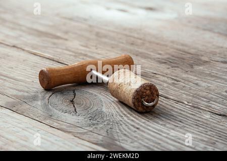 Corkscrew with a screwed wine cork on an old wooden unpainted table. Stock Photo
