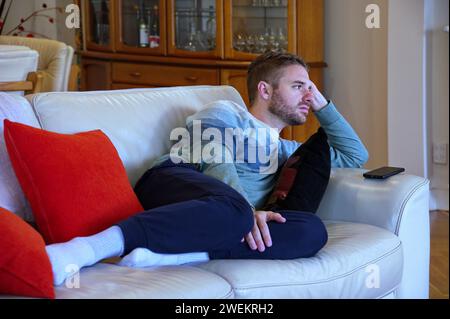 Young handsome man lying on the sofa and looking away Stock Photo