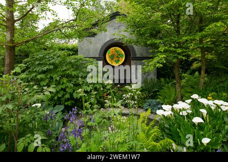 Trees and herbaceous plants including Iris siberica 'Silver Edge',  Zantedeschia Crowborough and Valeriana officinalis in front of neo classical templ Stock Photo